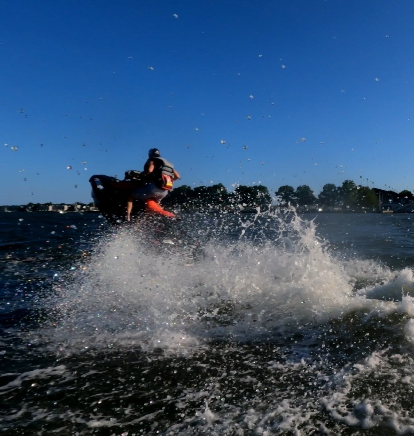 Jet ski rider jumping over choppy coastal waters with splash