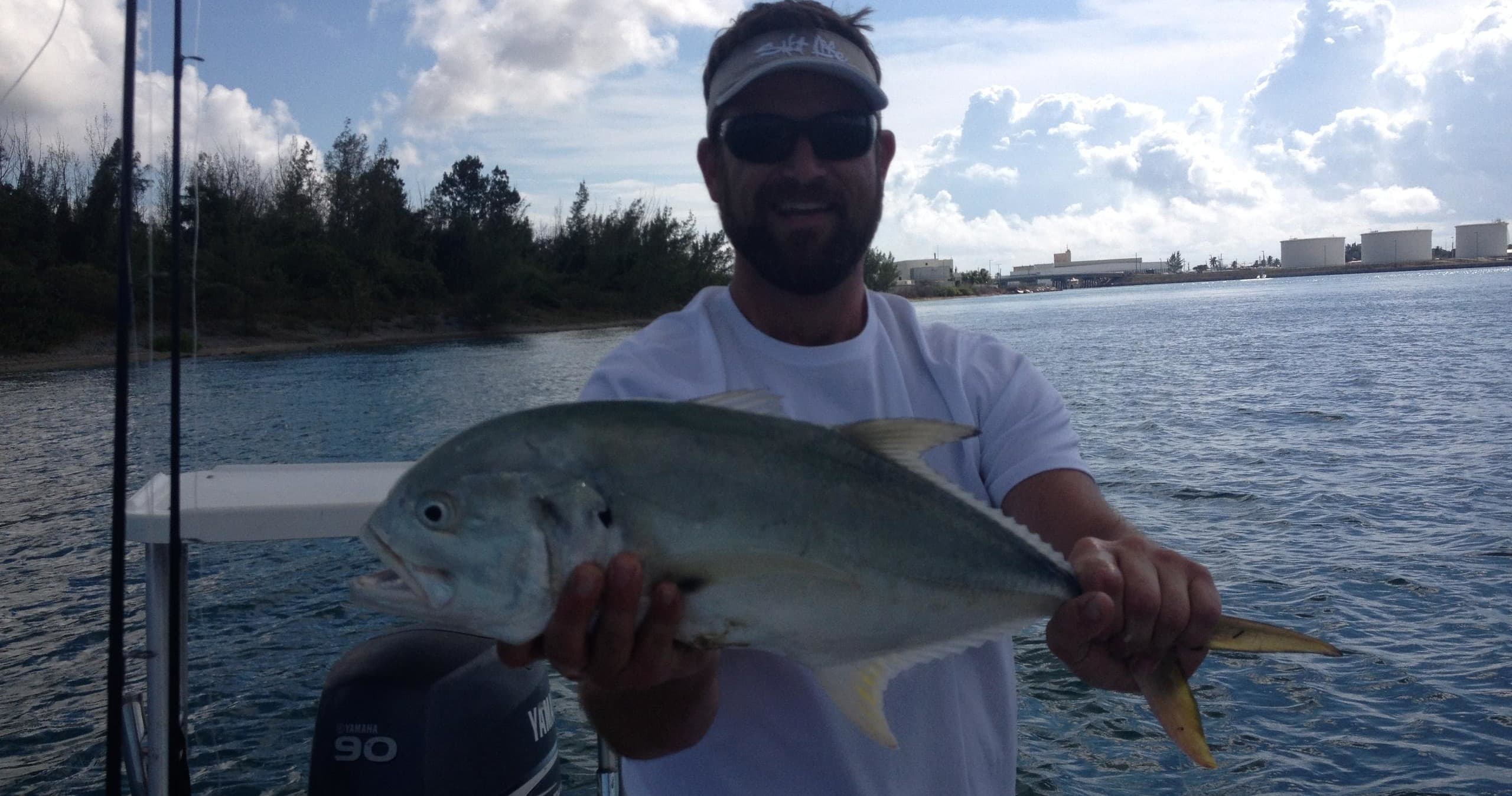 Angler holding jackfish on boat in coastal waters at day