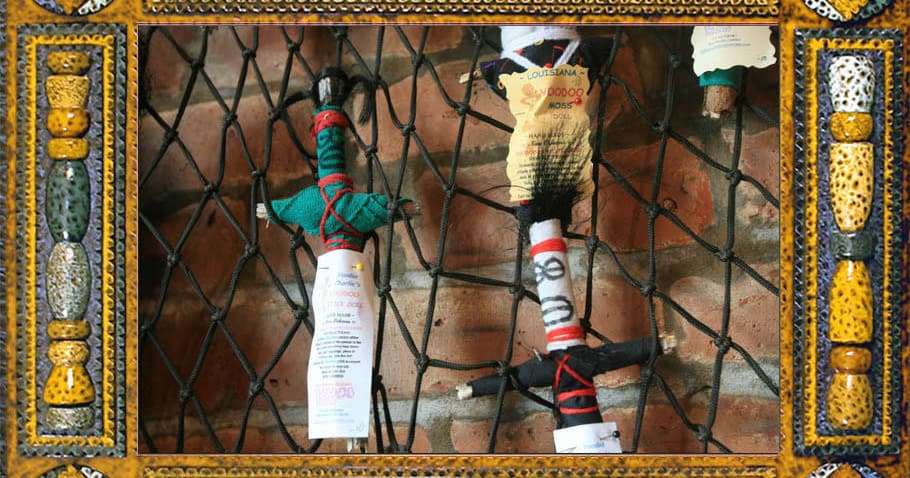 Hand-tied voodoo dolls on iron fence, ritual offerings display