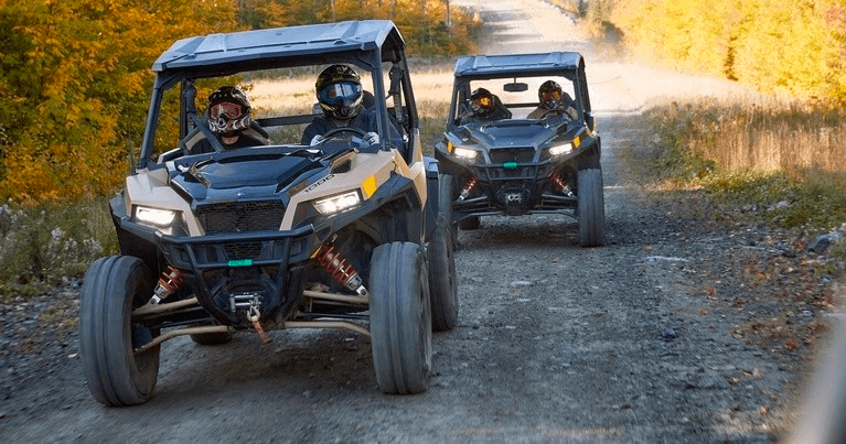 Two UTVs following scenic gravel trail through autumn fields
