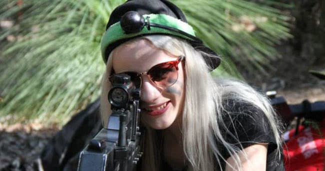 Woman aiming outdoor laser rifle among bushland trees
