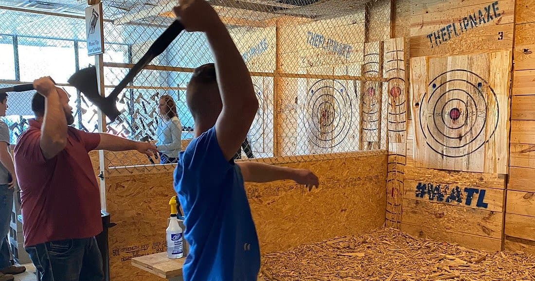 Patrons swinging axes at indoor axe throwing lanes in Jacksonville
