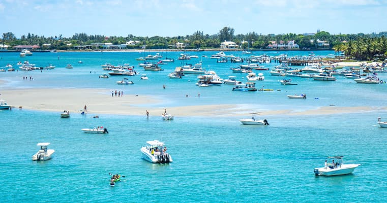 Boats in turquoise coastal bay with people enjoying beach boating