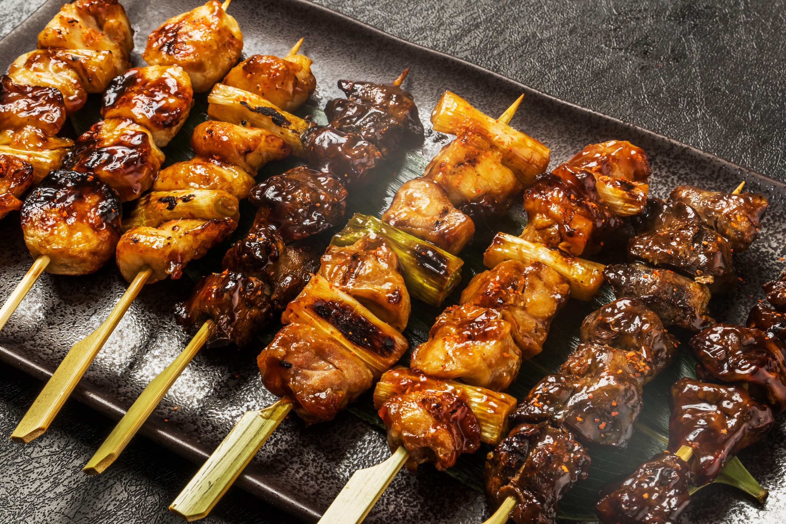 Grilled meat skewers sizzling on barbecue at street grill