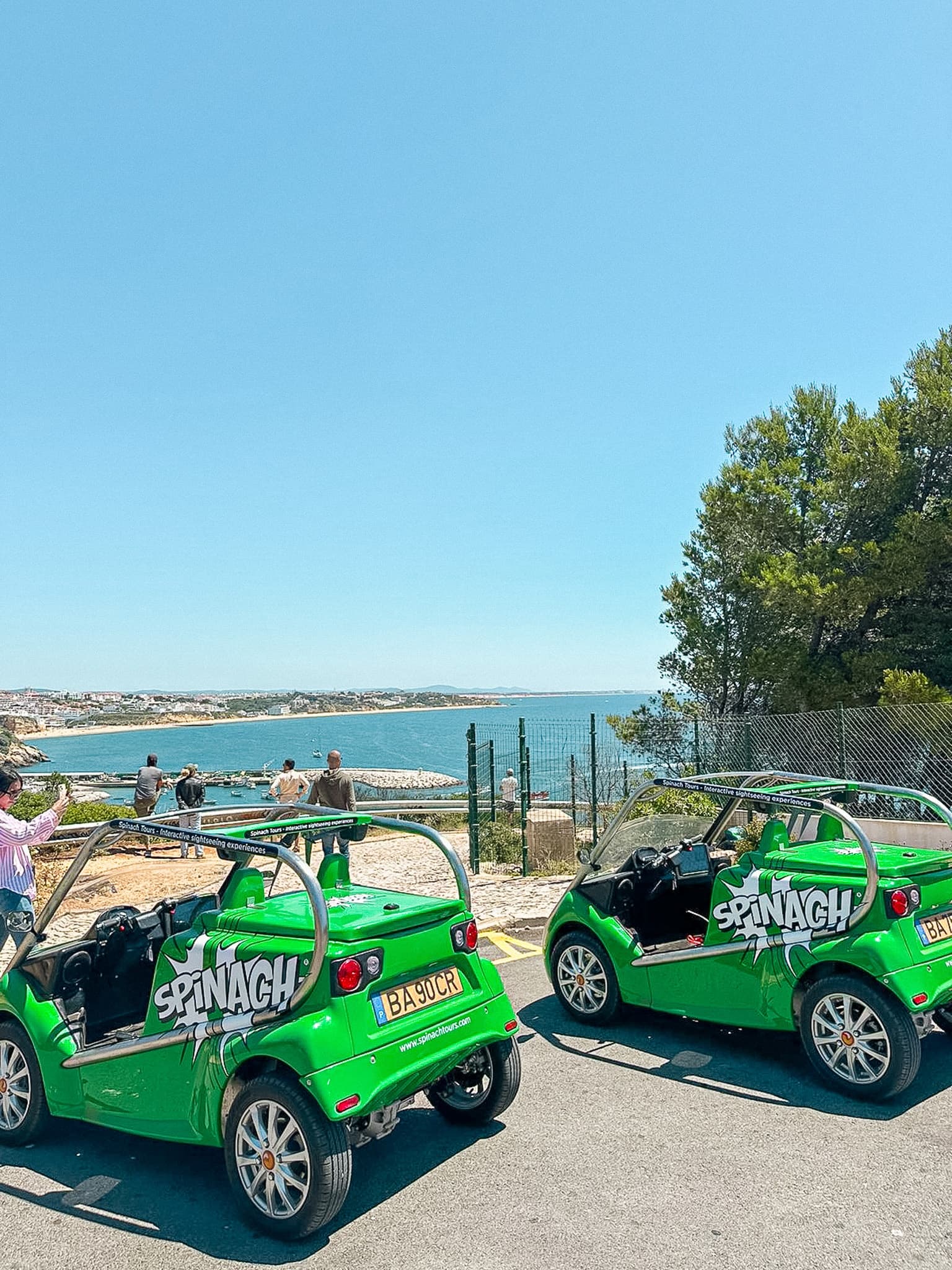 Open-top electric tour cars parked by seaside cliffs in Albufeira