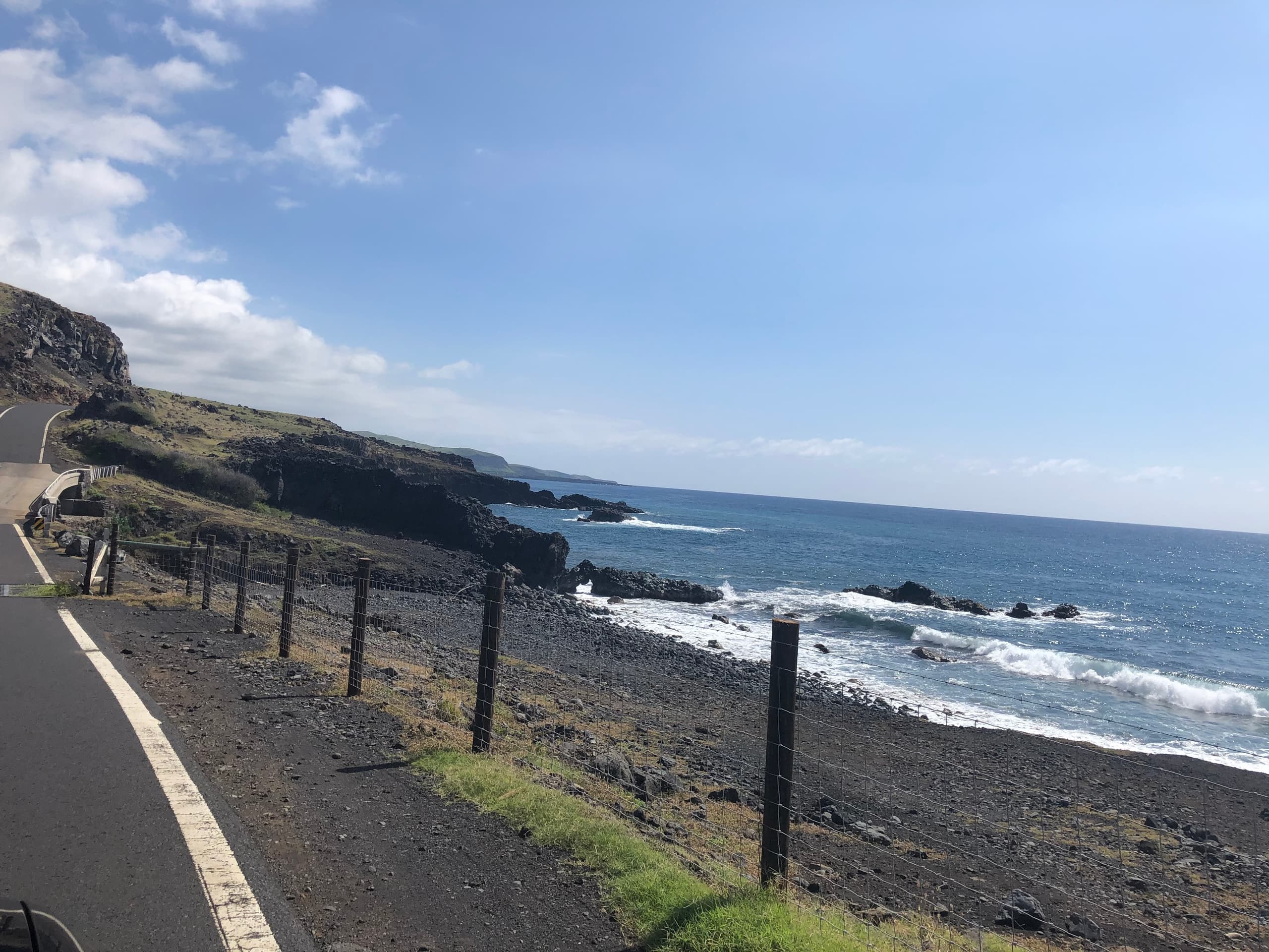Coastal highway winding past rocky shoreline and crashing ocean waves