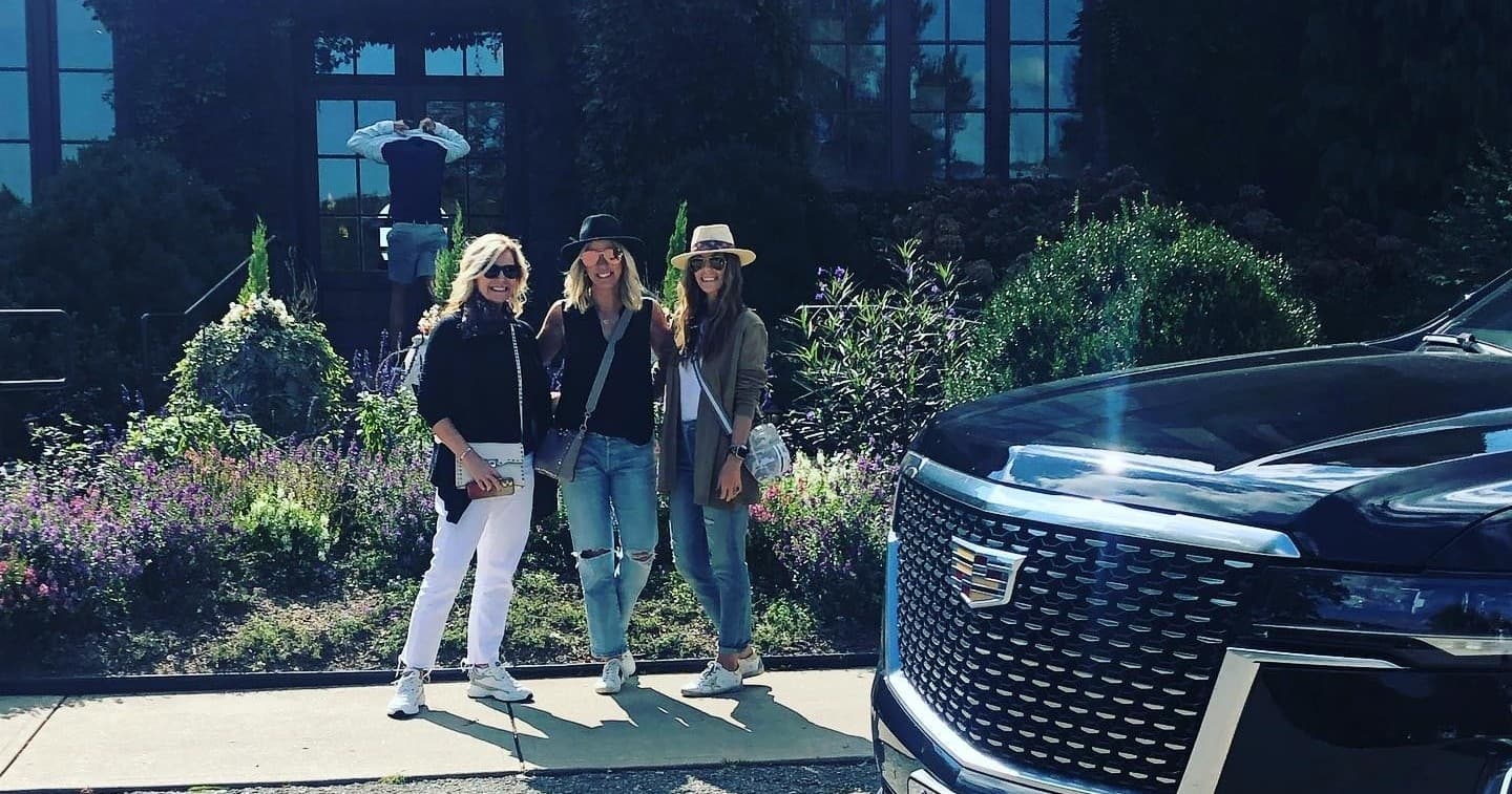 Guests posing beside luxury SUV at landscaped resort entrance