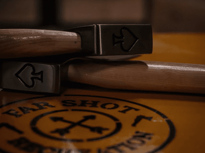 Branded axe heads stacked on table at indoor throwing range