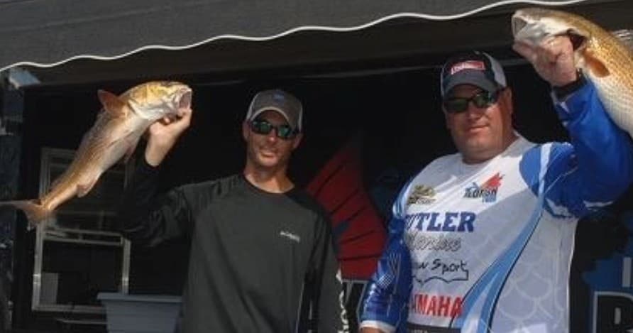 Anglers holding redfish on a charter boat deck