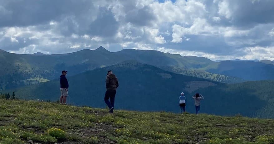 Hikers standing on mountain ridge overlooking wide valley views