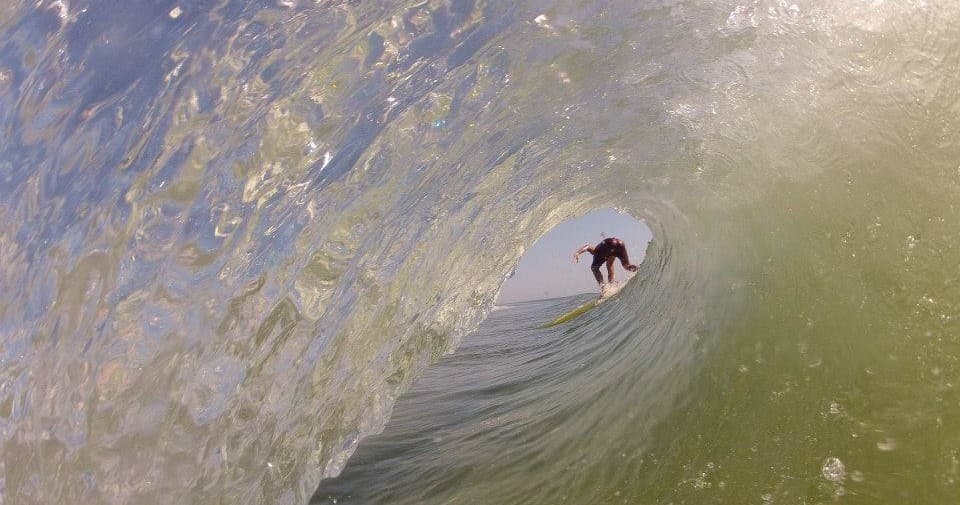 Surfer inside barreling wave tube, translucent green water view