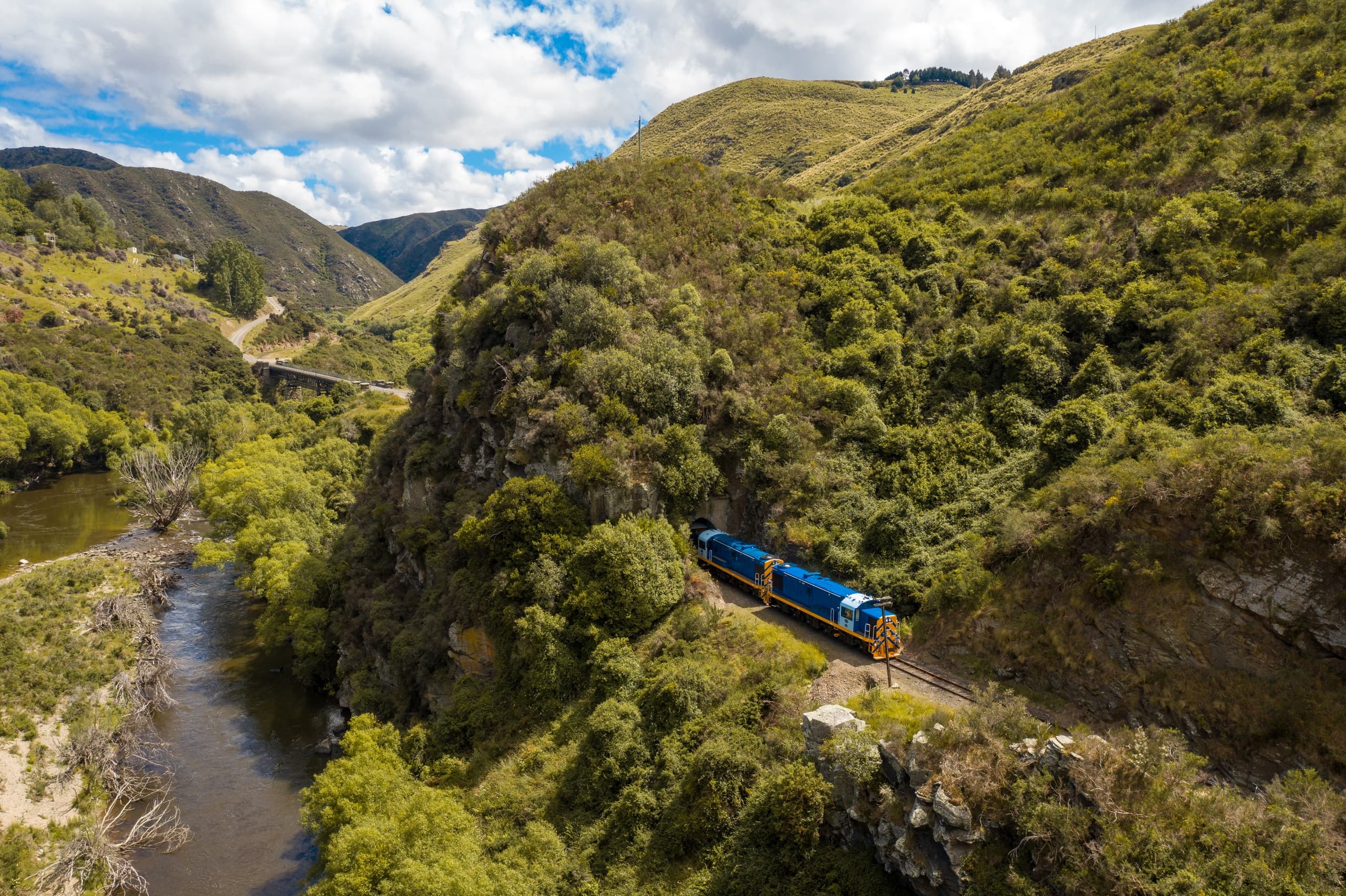 Blue heritage train winding through steep green river gully