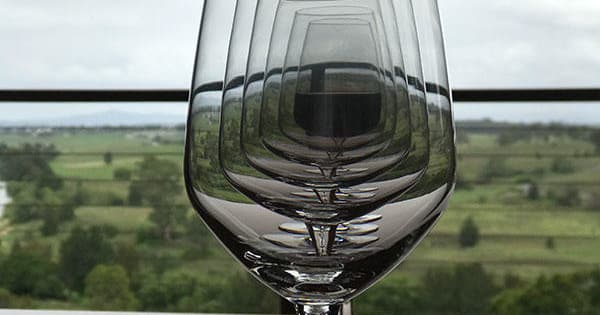 Wine glass framing rolling vineyard landscape, scenic tasting