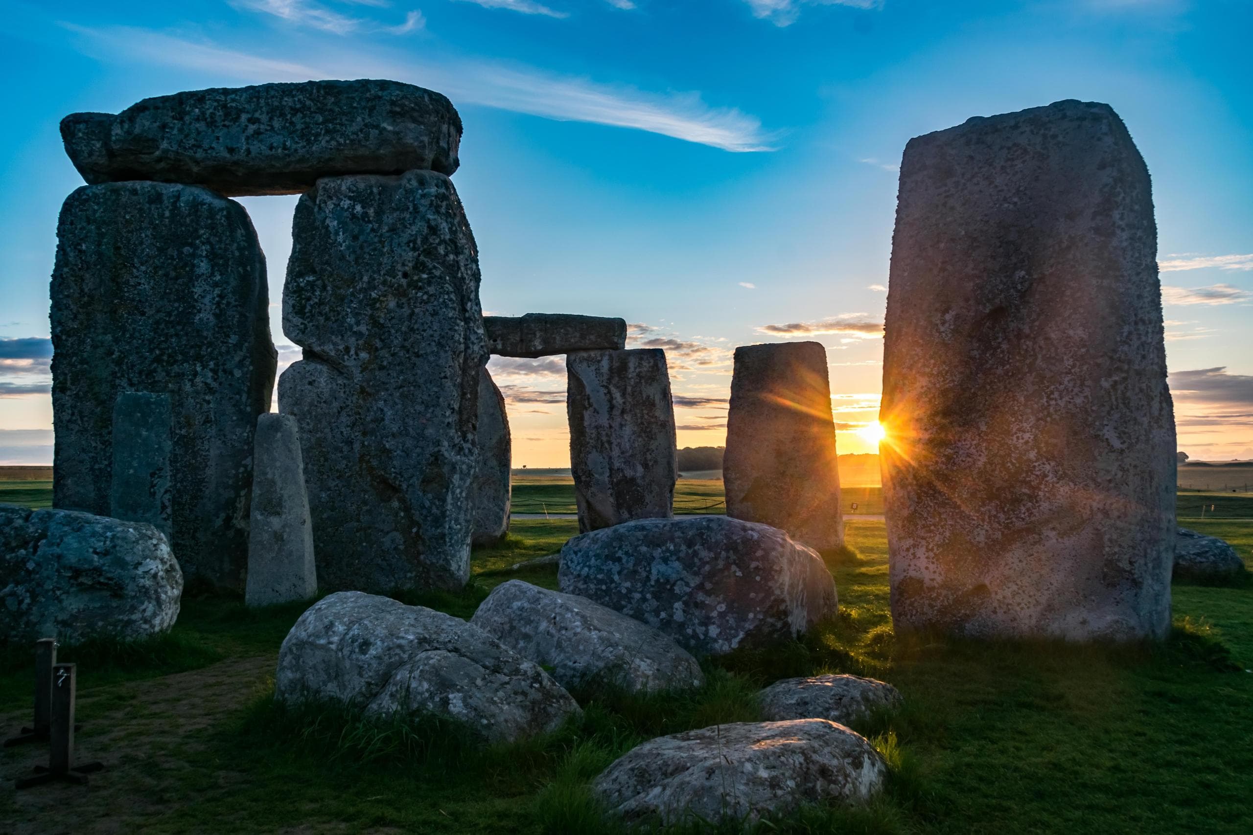 Sunset at Stonehenge standing stones on grassy plain, UK