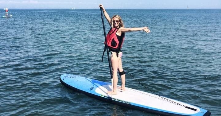 Young woman stand-up paddleboarding on open blue sea