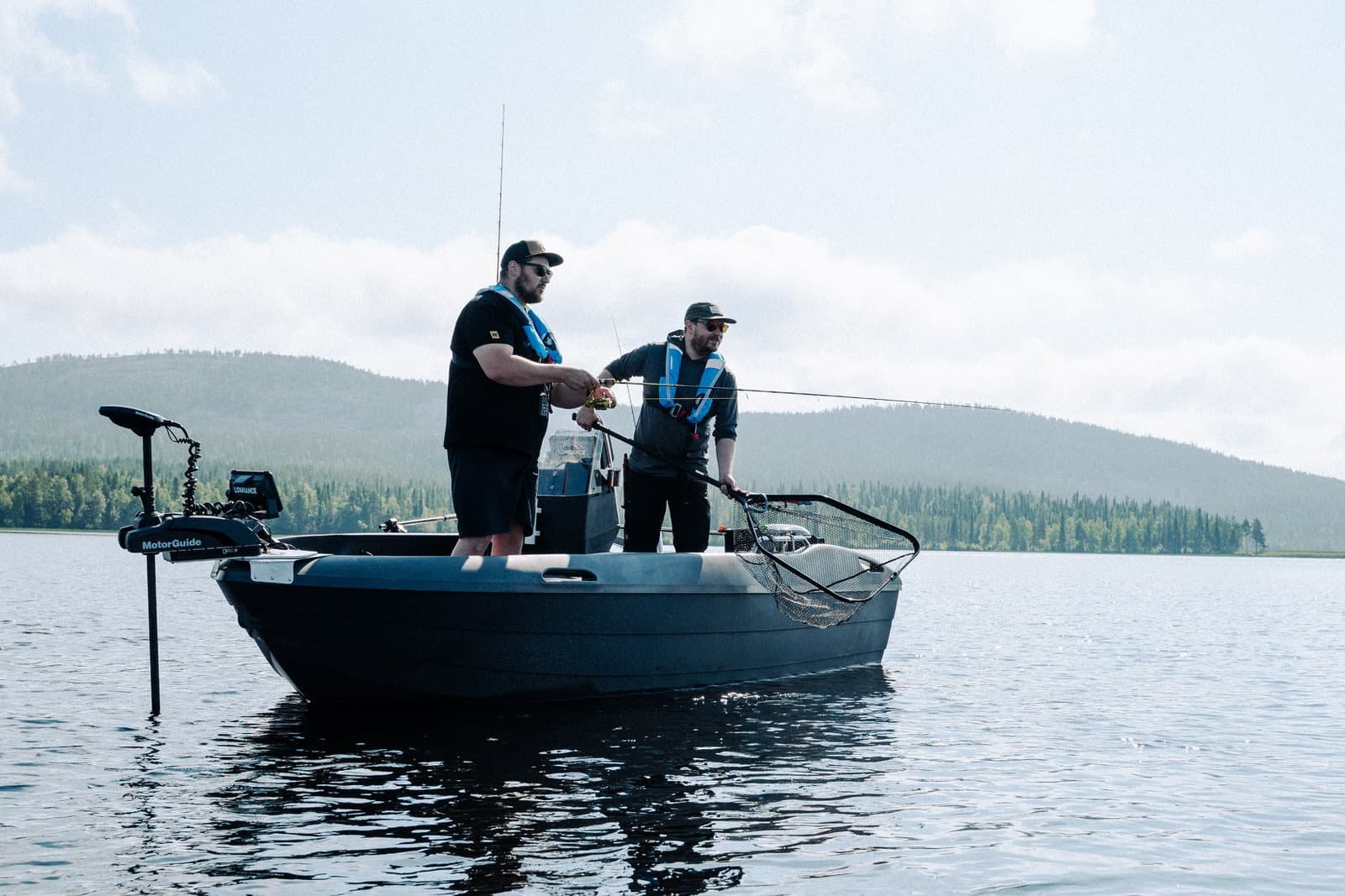 Anglers fishing from boat on tranquil lake with forested shore
