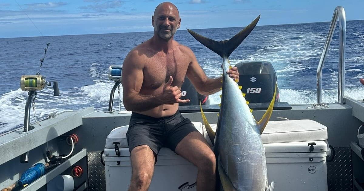 Angler on sportfishing boat holding trophy tuna offshore with ocean backdrop