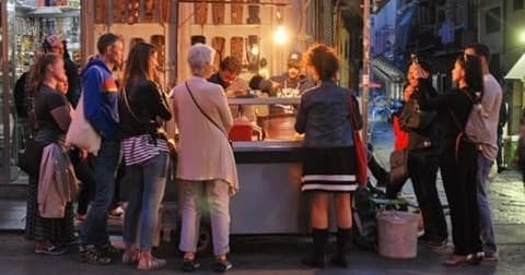 Crowd enjoying nighttime street food stall in city square