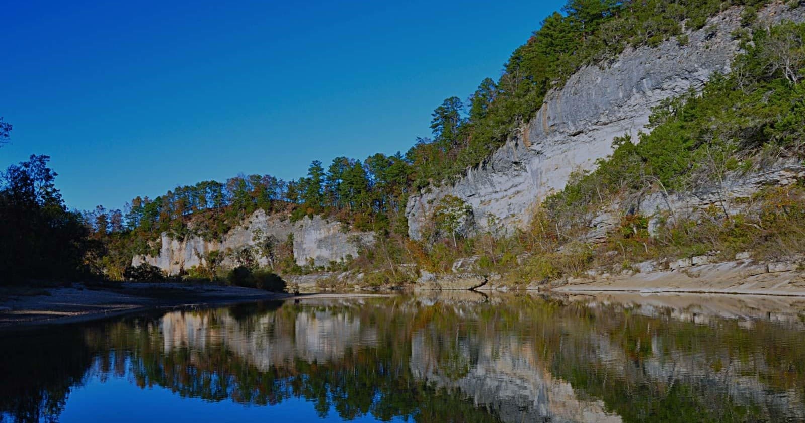 Scenic river canyon and bluff reflected in calm water for floats