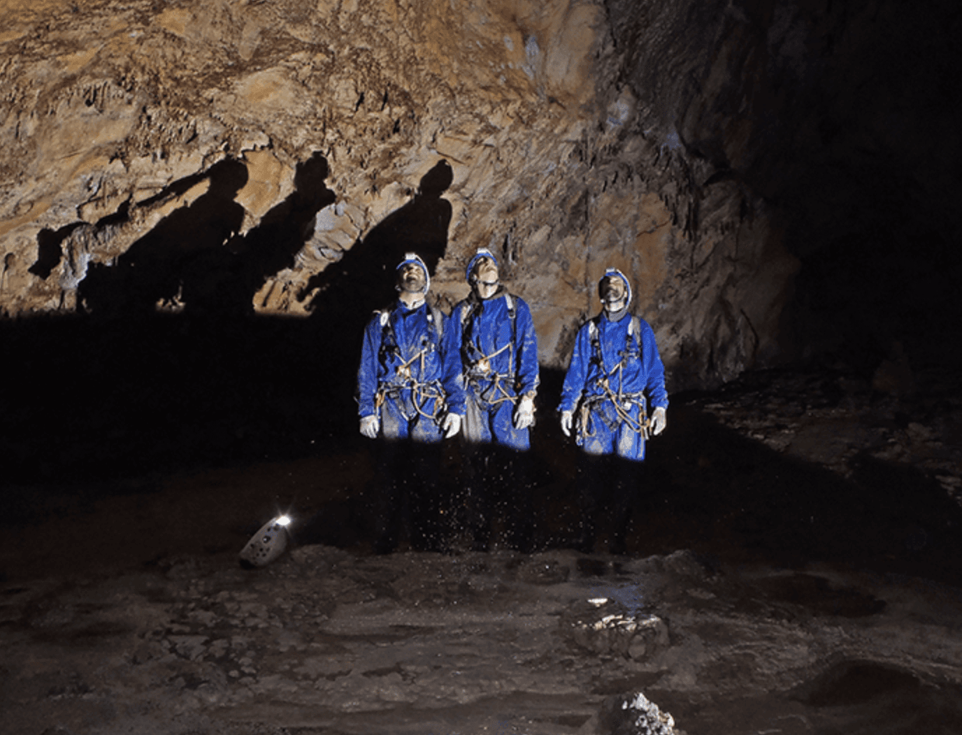 Cavers exploring dim limestone cave passage with headlamps on