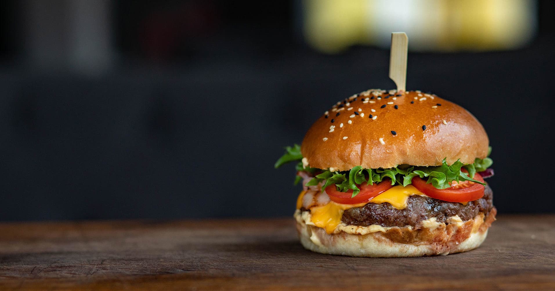 Gourmet cheeseburger close-up on wooden table, restaurant food tour