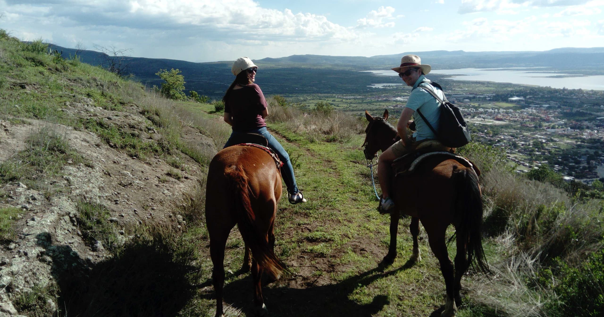 Two riders on horseback overlooking expansive valley panorama
