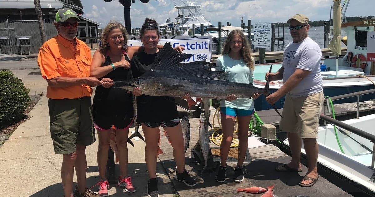 Fishing charter group posing with large billfish on marina dock