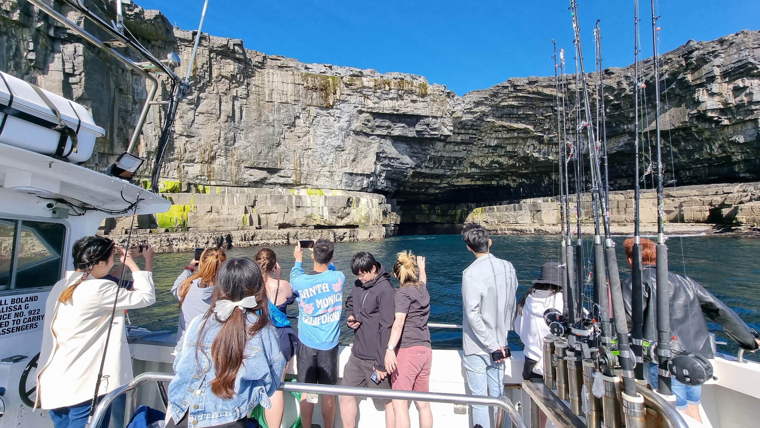 Guided boat tour approaching limestone cliffs with passengers observing