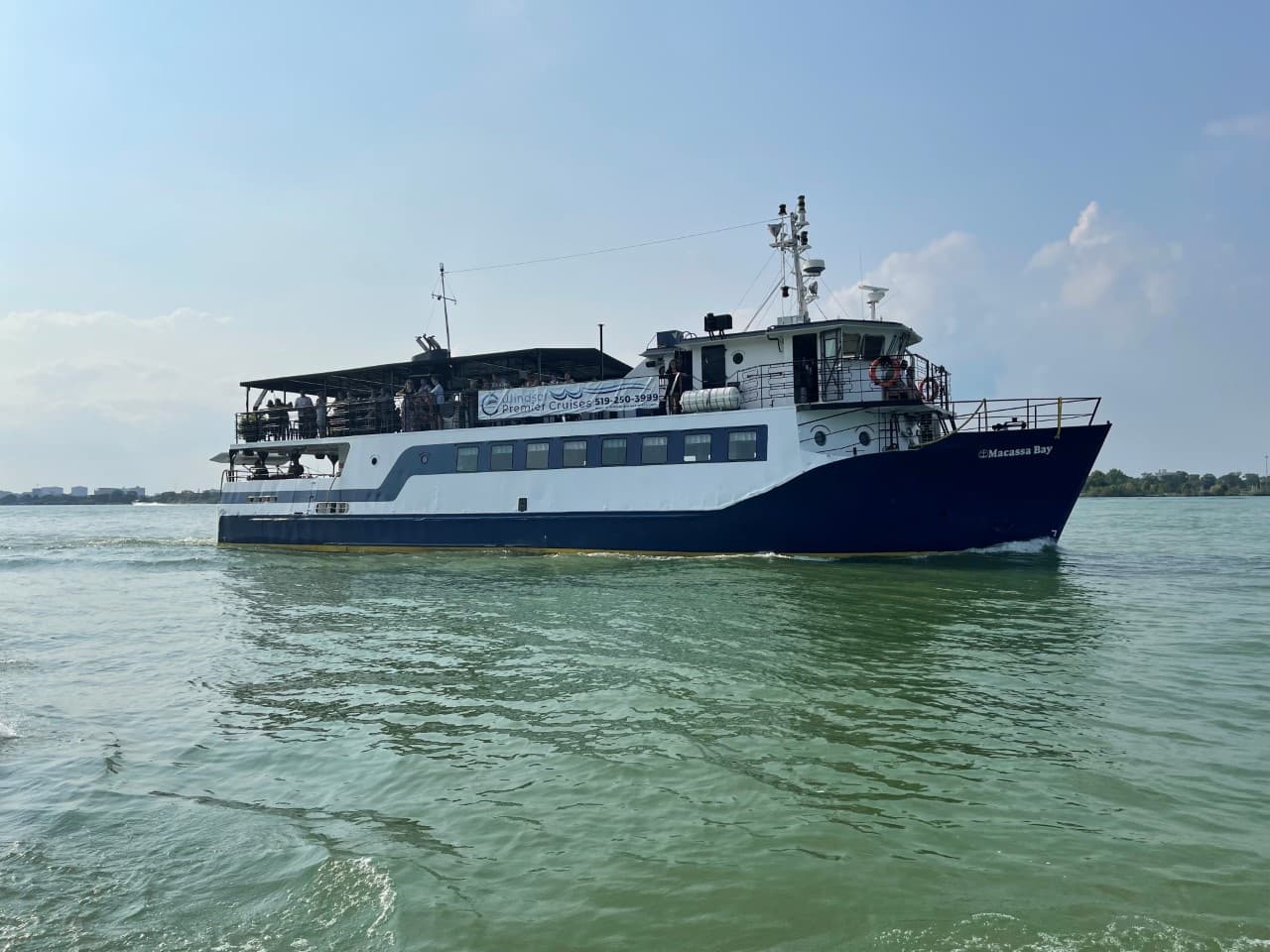 Daytime cruise ship sailing on calm river waters near Windsor