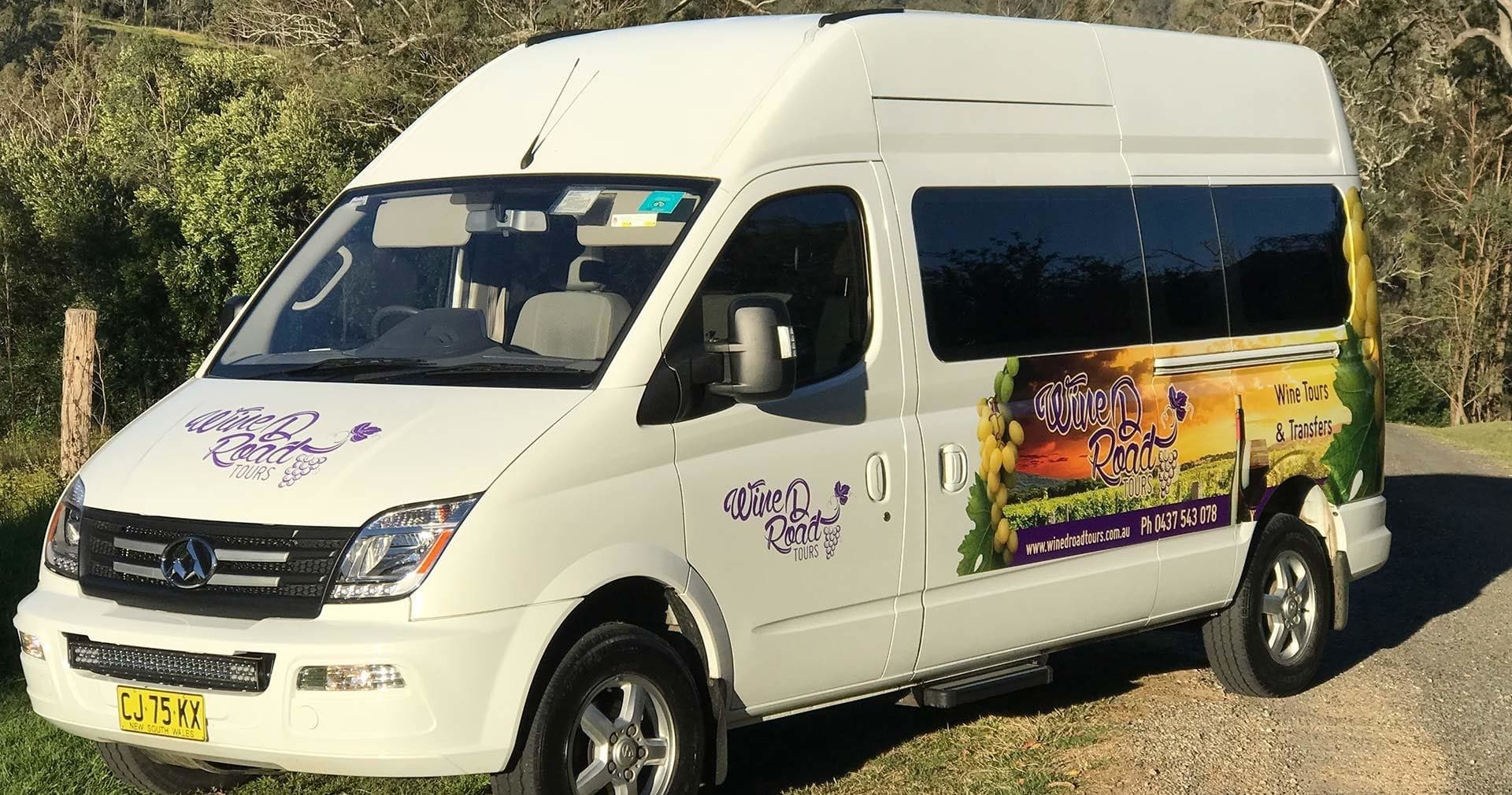 Branded tour van parked by rural vineyard, scenic road trip