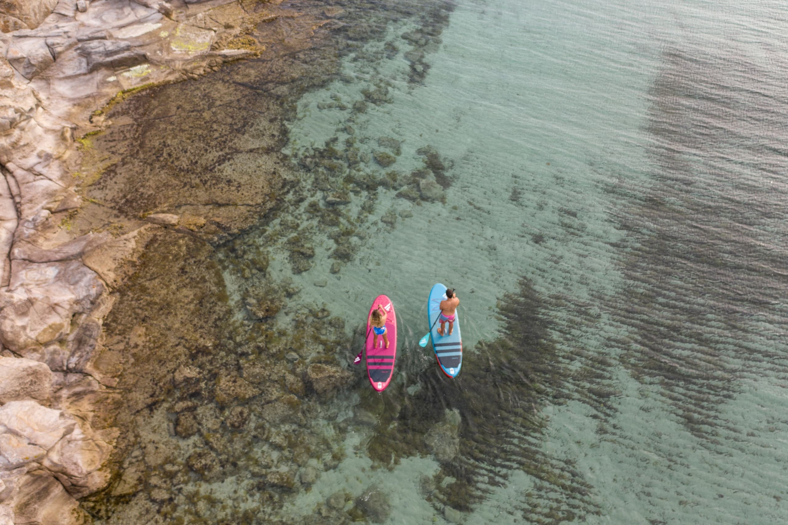 Two paddleboards gliding over clear shallow Sardinia waters