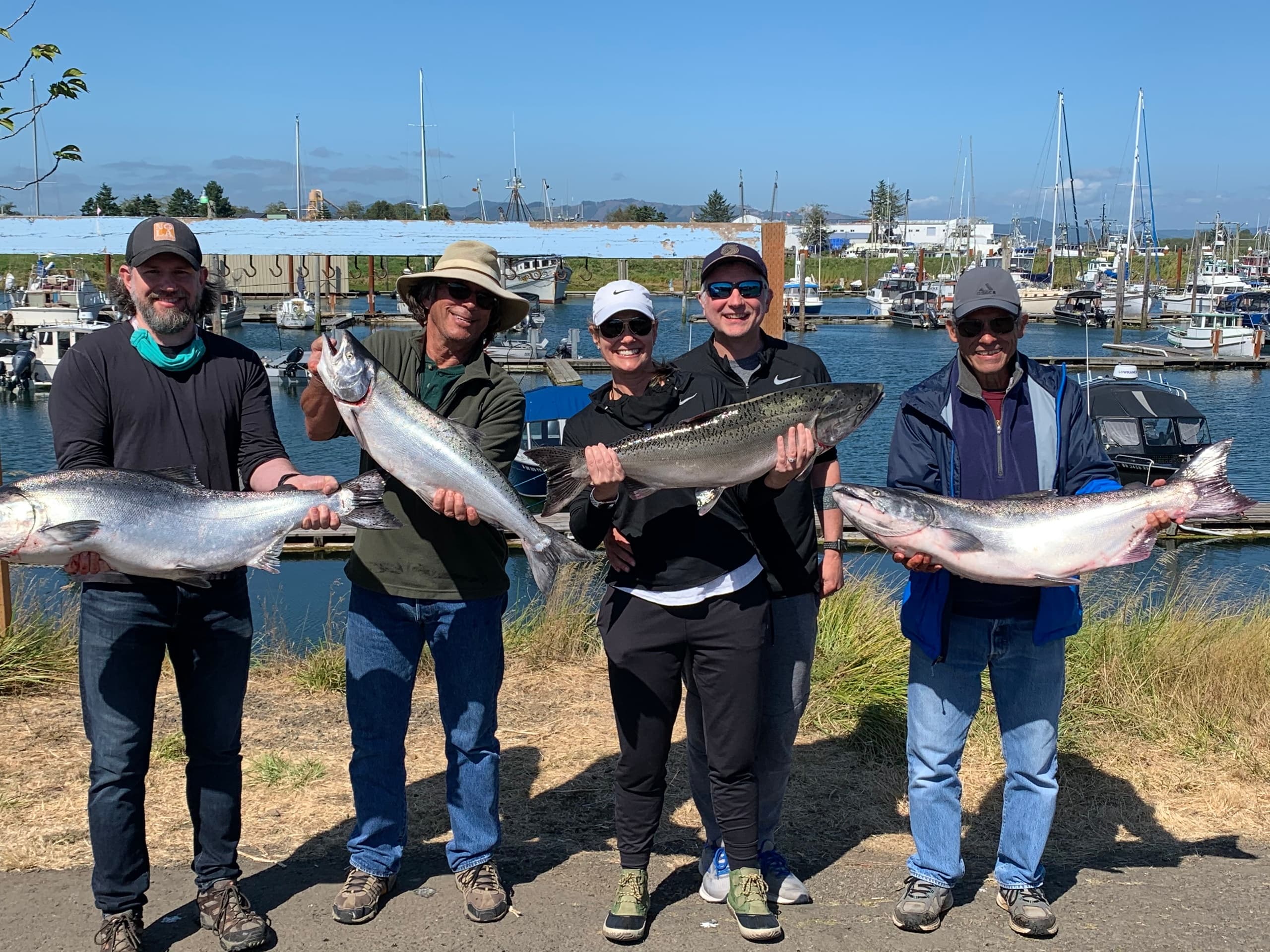 Group anglers holding trophy salmon at marina after charter trip