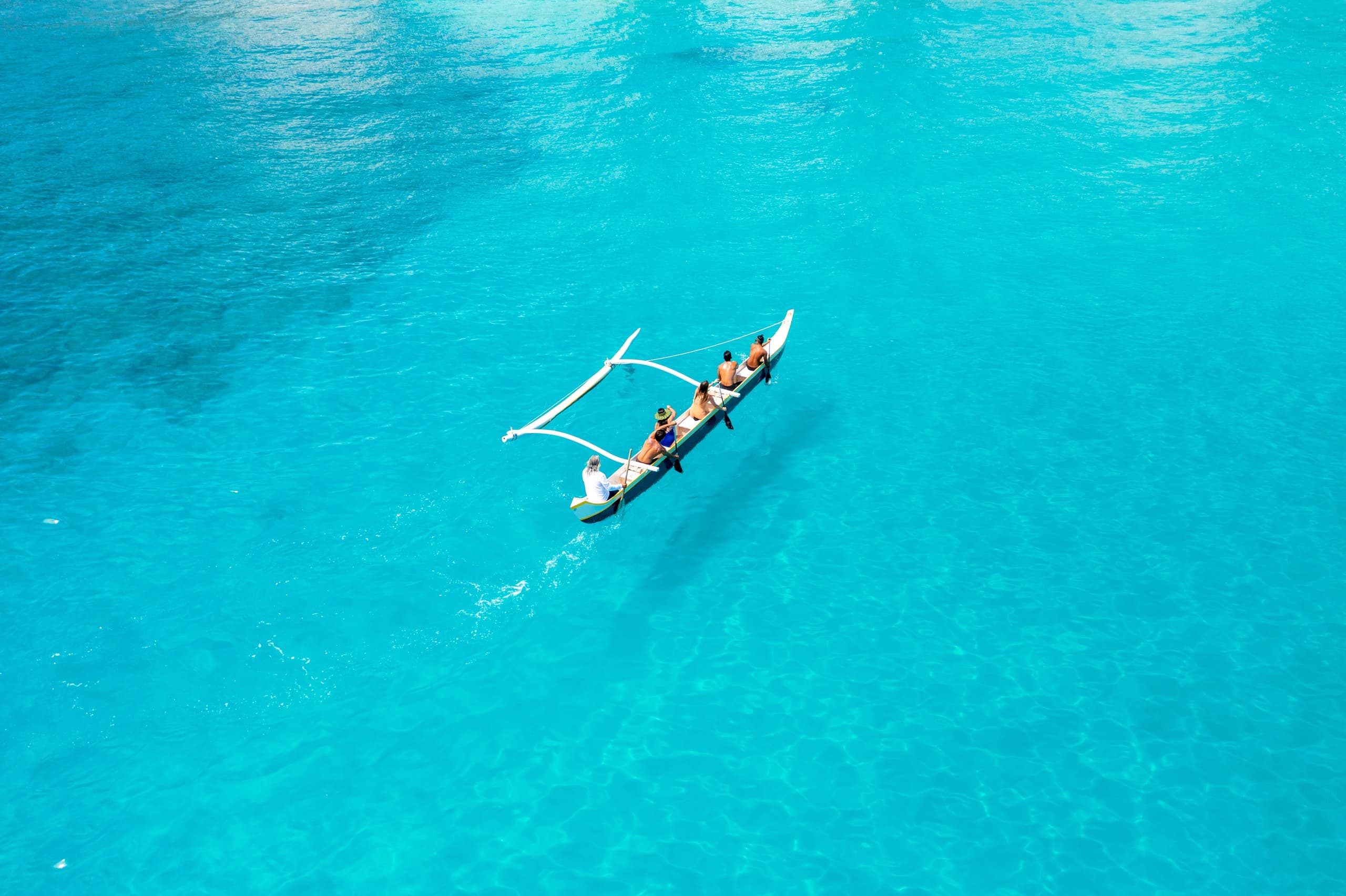 Aerial outrigger canoe team paddling turquoise waters off Waikiki