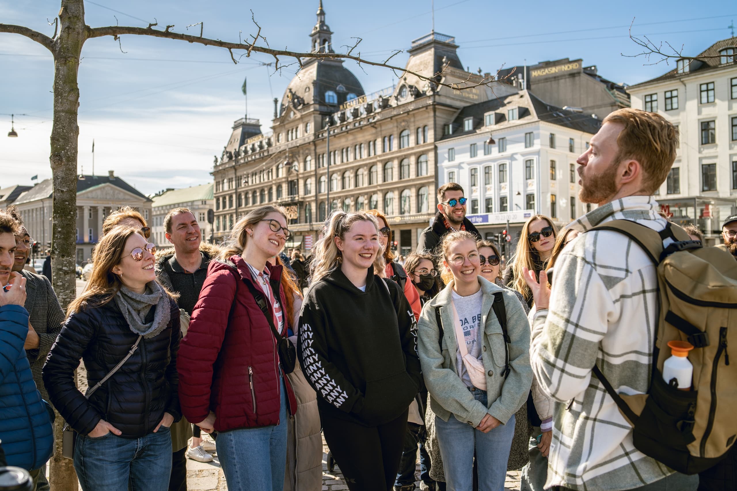 Guided walking tour group exploring Copenhagen city square outdoors
