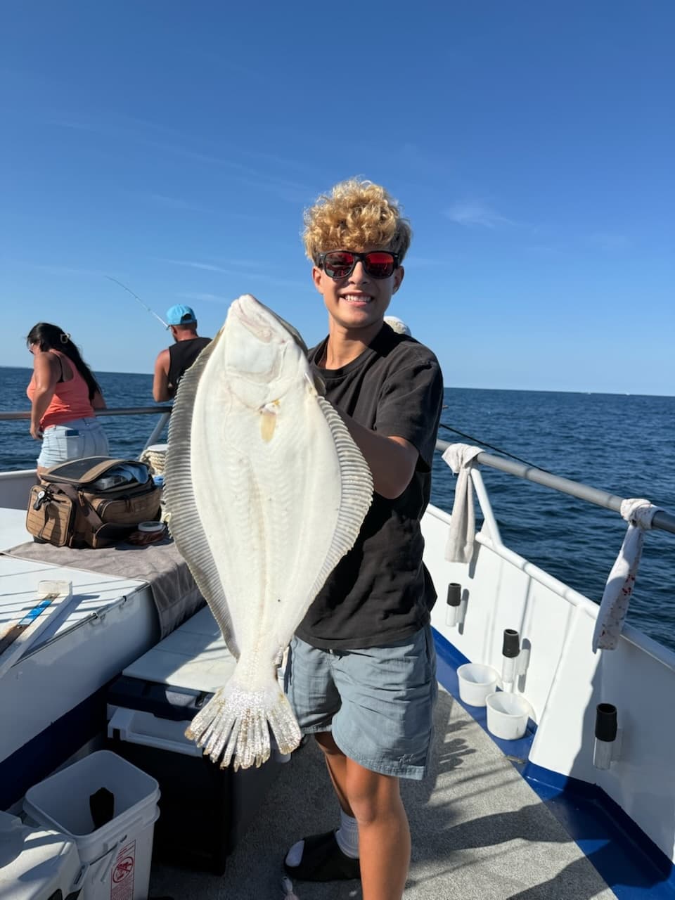 Teen angler displaying large flounder aboard offshore fishing charter