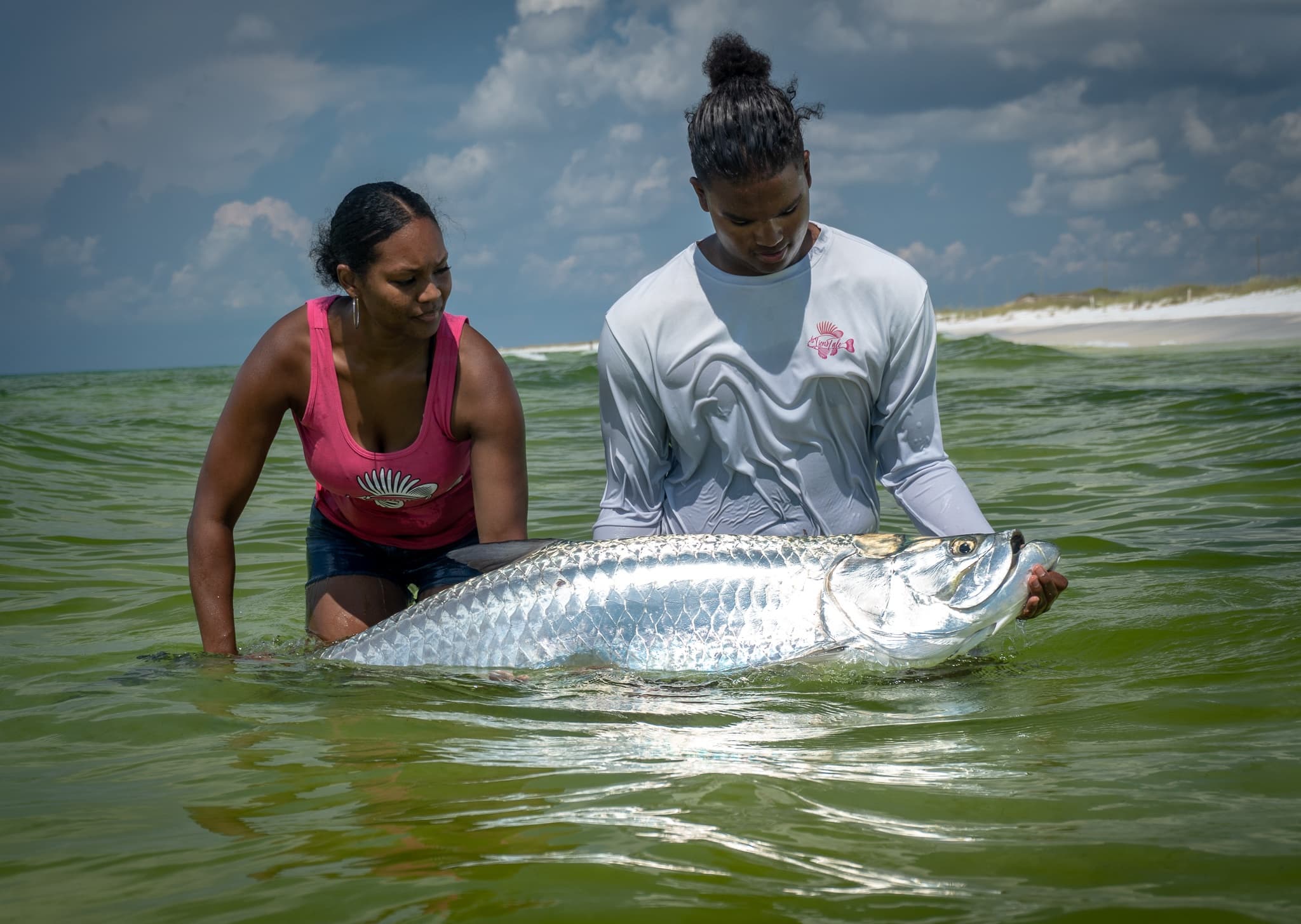 Anglers releasing giant tarpon in shallow coastal waters near beach