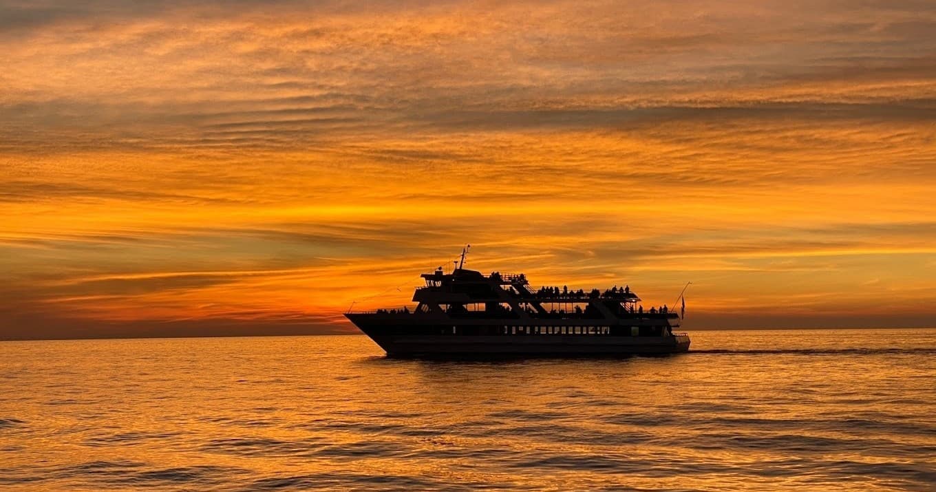 Sunset cruise ship silhouetted on calm ocean at dusk