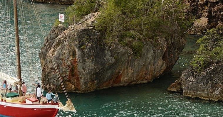 Sailboat anchored near dramatic coastal cliffs and turquoise water