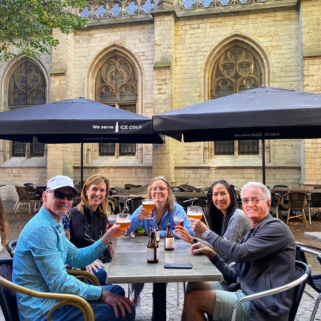 Small group enjoying outdoor café drinks by Antwerp church facade