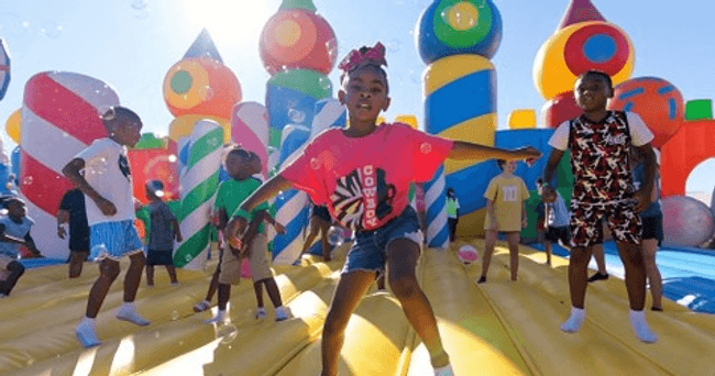 Kids bouncing on colorful outdoor inflatable park at festival