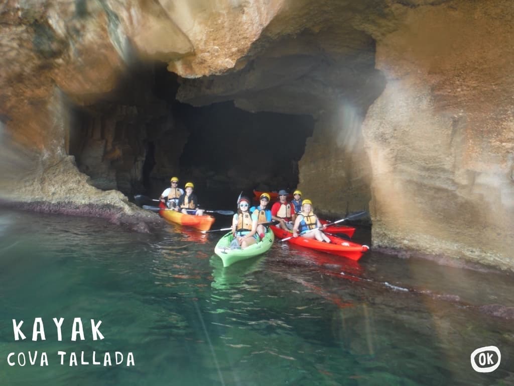 Guided cave kayaking group entering coastal sea cave