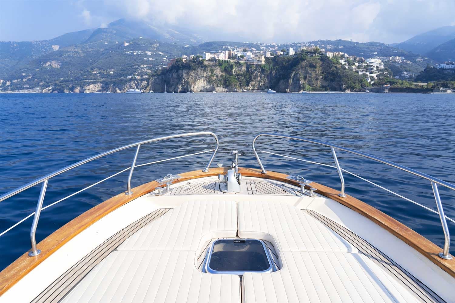 Bow view from yacht toward coastal town and calm blue horizon