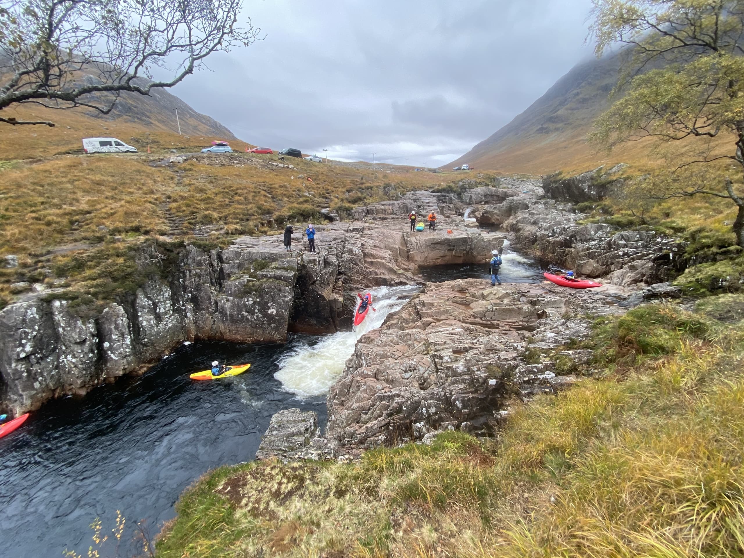 Kayakers navigating rocky river gorge amid hills