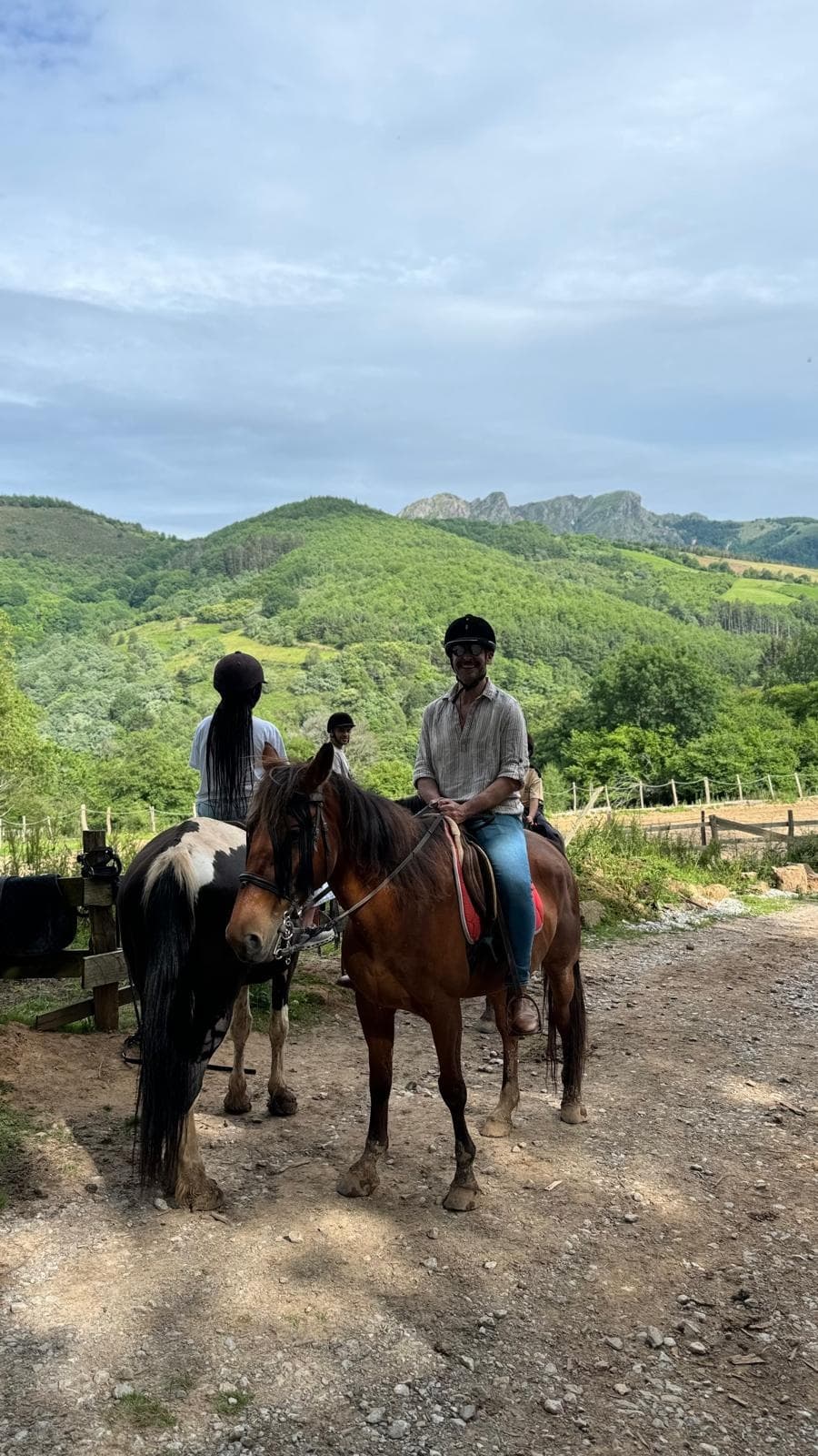 Two riders pausing on dirt path with rolling Basque hills backdrop