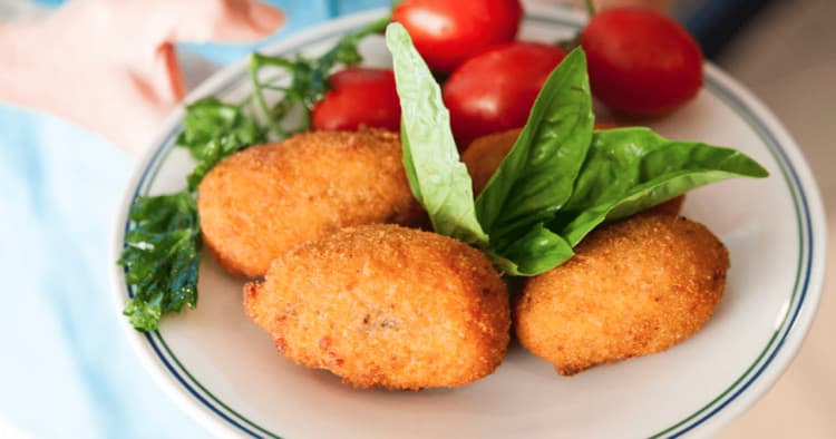 Fried Italian croquettes with basil and cherry tomatoes on plate