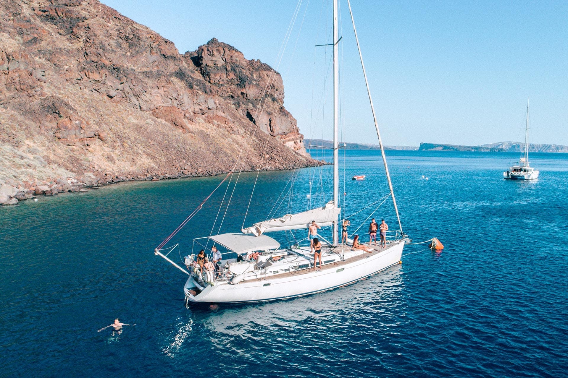 Yacht anchored in secluded bay with passengers on deck