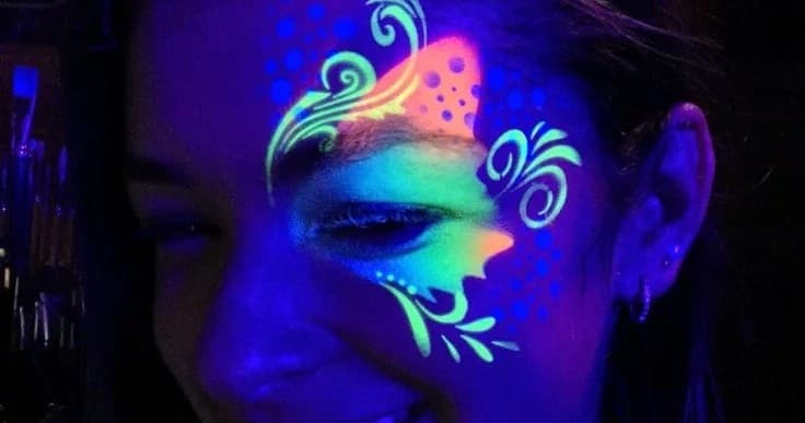 Neon UV face painting on girl at nighttime party indoors