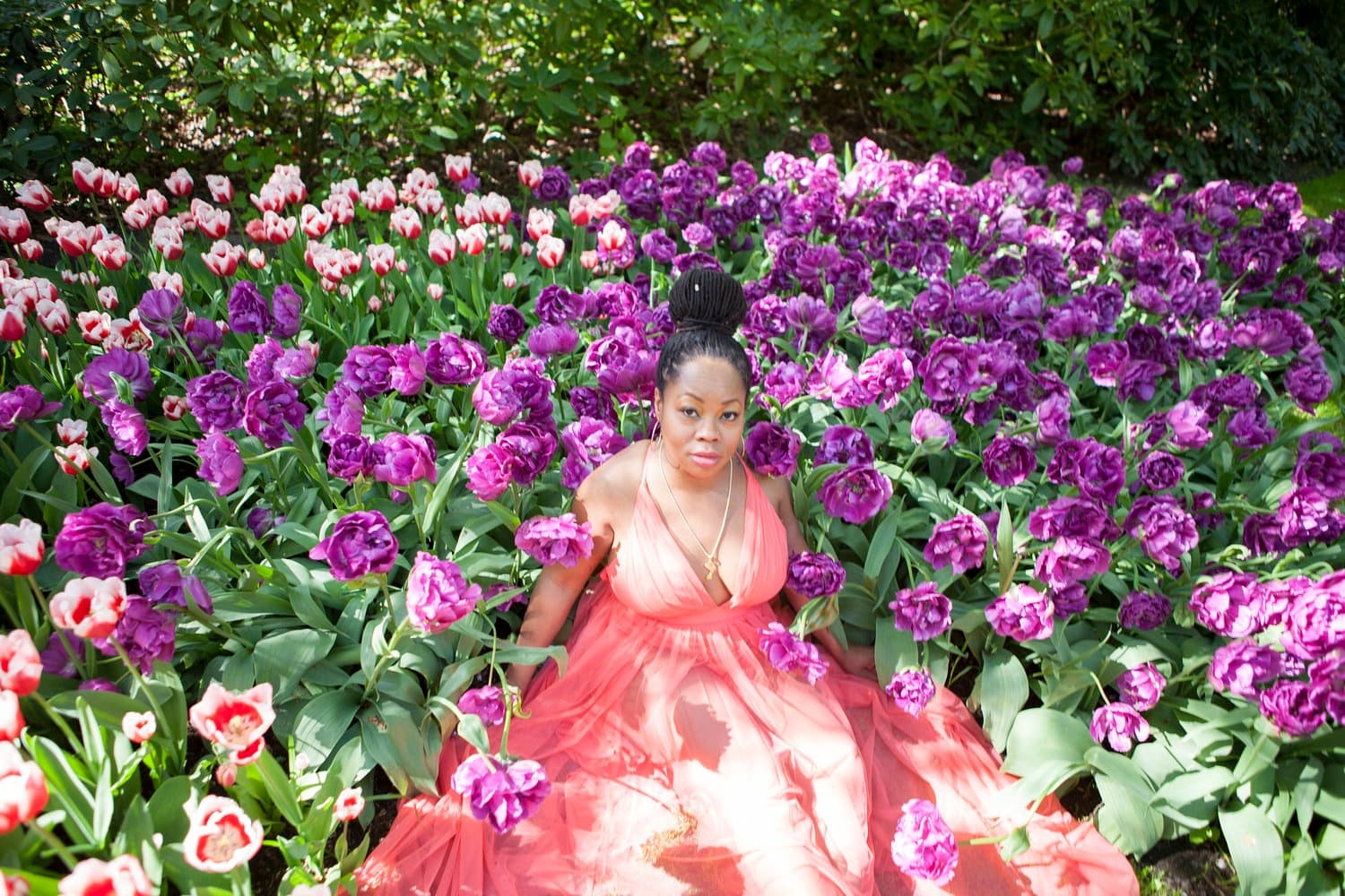 Woman in floral gown seated among tulips in Melbourne botanic garden