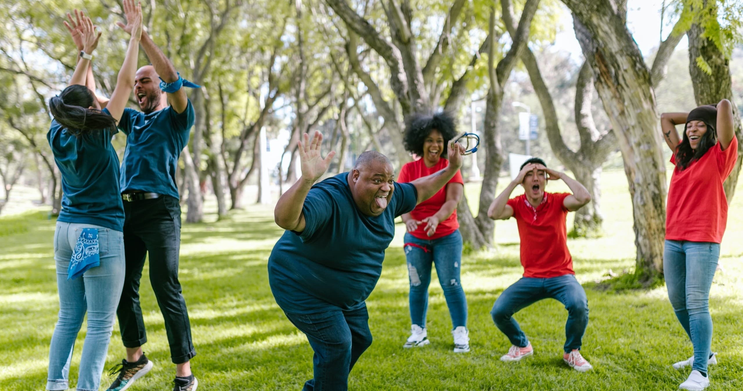 Outdoor group fitness games in grassy park under trees