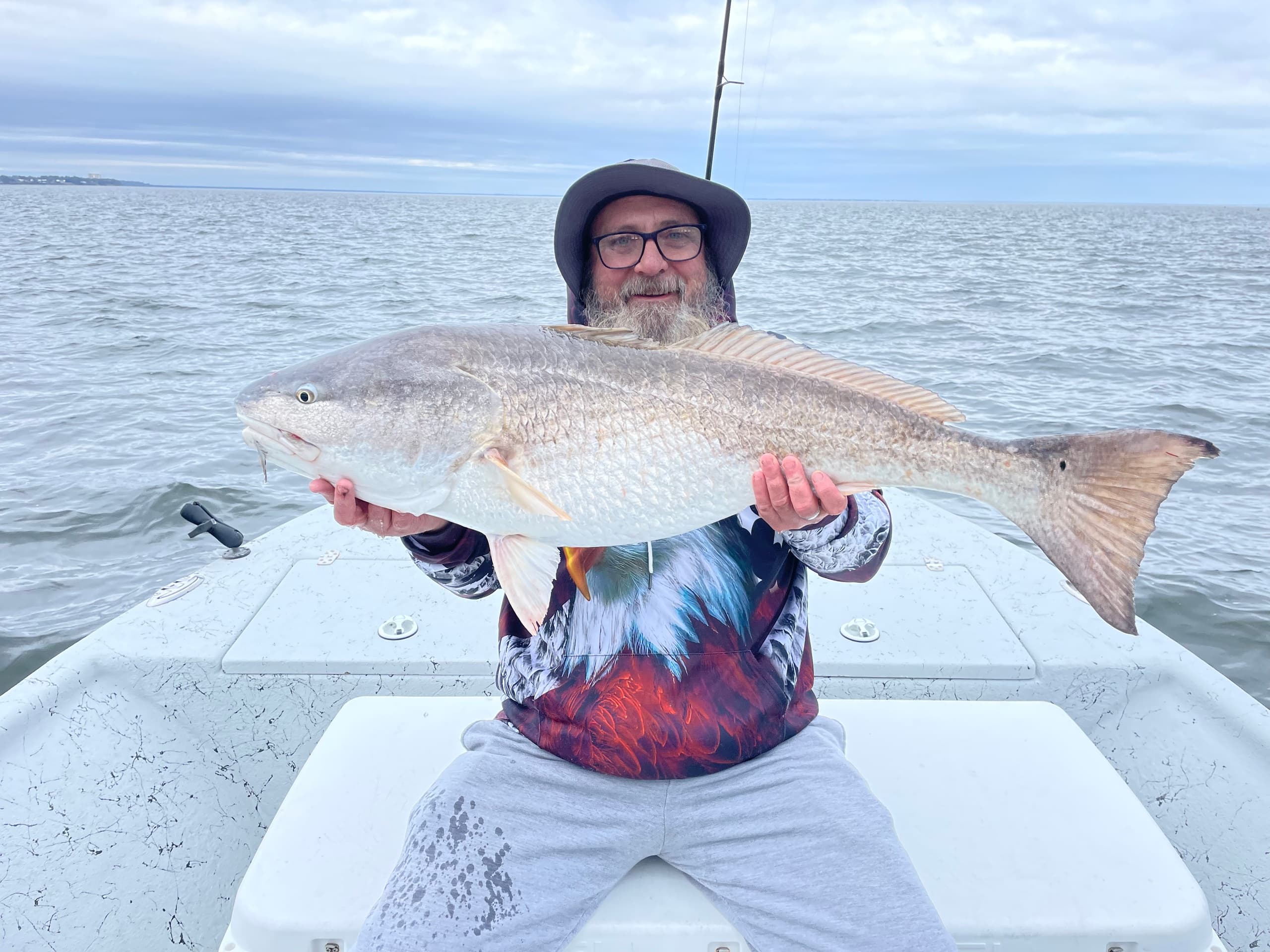 Angler proudly displaying trophy redfish aboard shallow water fishing trip